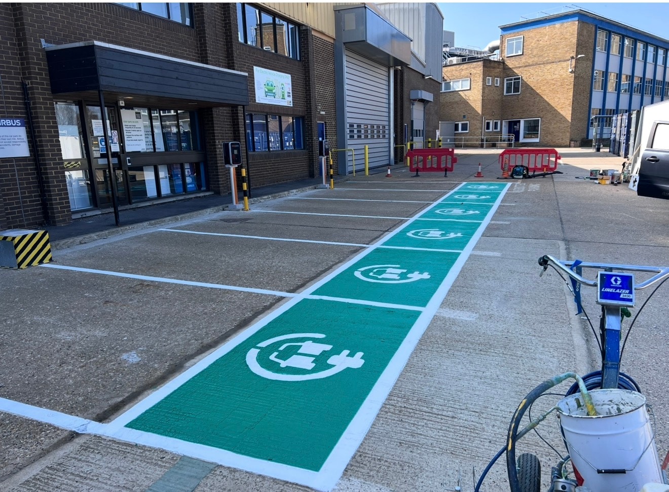 Freshly painted green EV charging bays with white EV symbols at an industrial facility — Stevenage